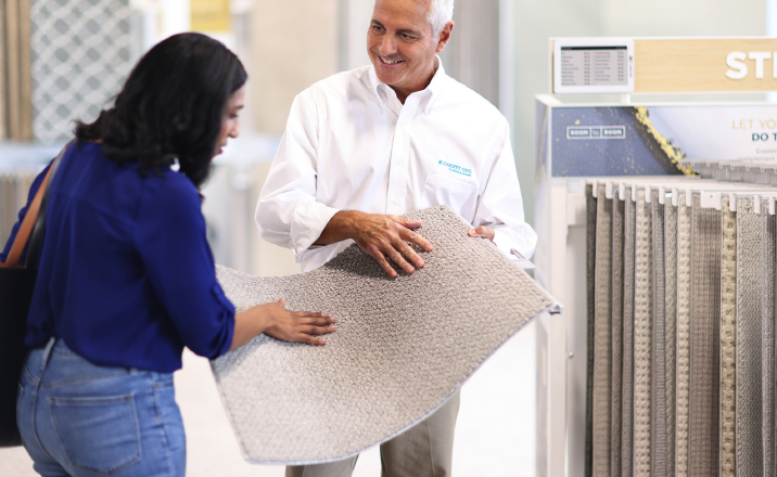 Friendly and knowledgeable flooring expert showing sample to customer.